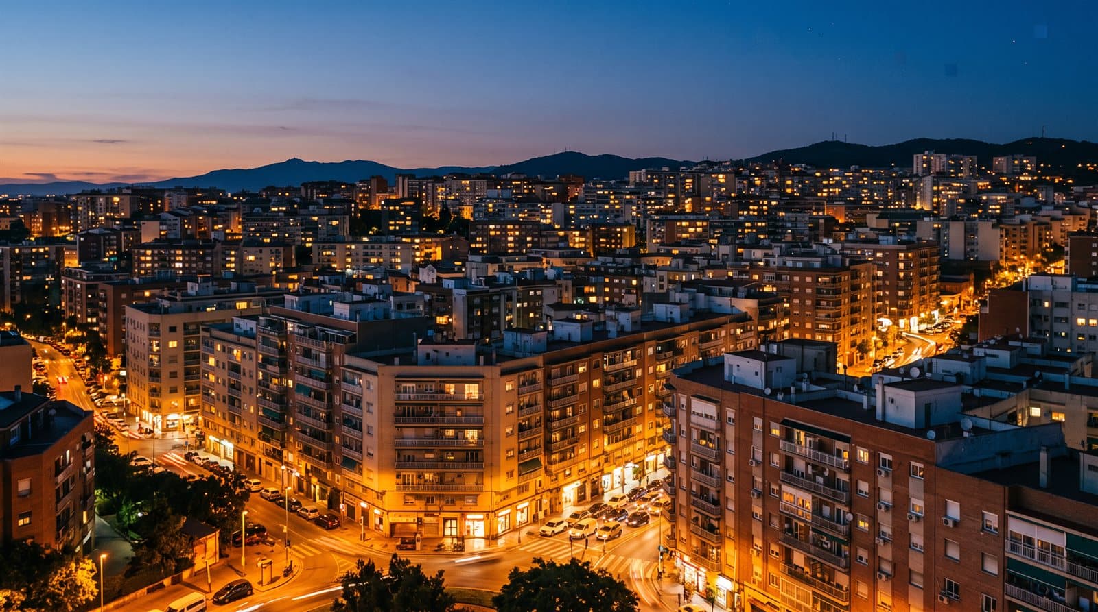 Ciudad residencial española al anochecer con cientos de ventanas de los bloques de pisos encendidas, en la hora de mayor demanda eléctrica.