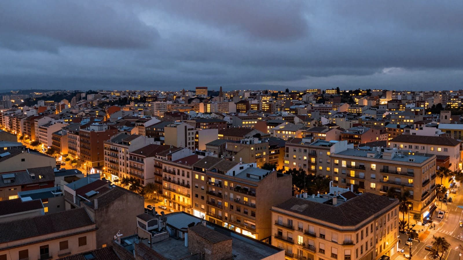 Ciudad española al anochecer de otoño con las ventanas de los pisos iluminadas a la hora de la cena