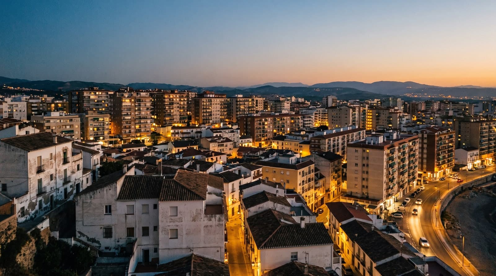 Ciudad española al anochecer con ventanas encendidas, la hora punta de consumo eléctrico en los hogares